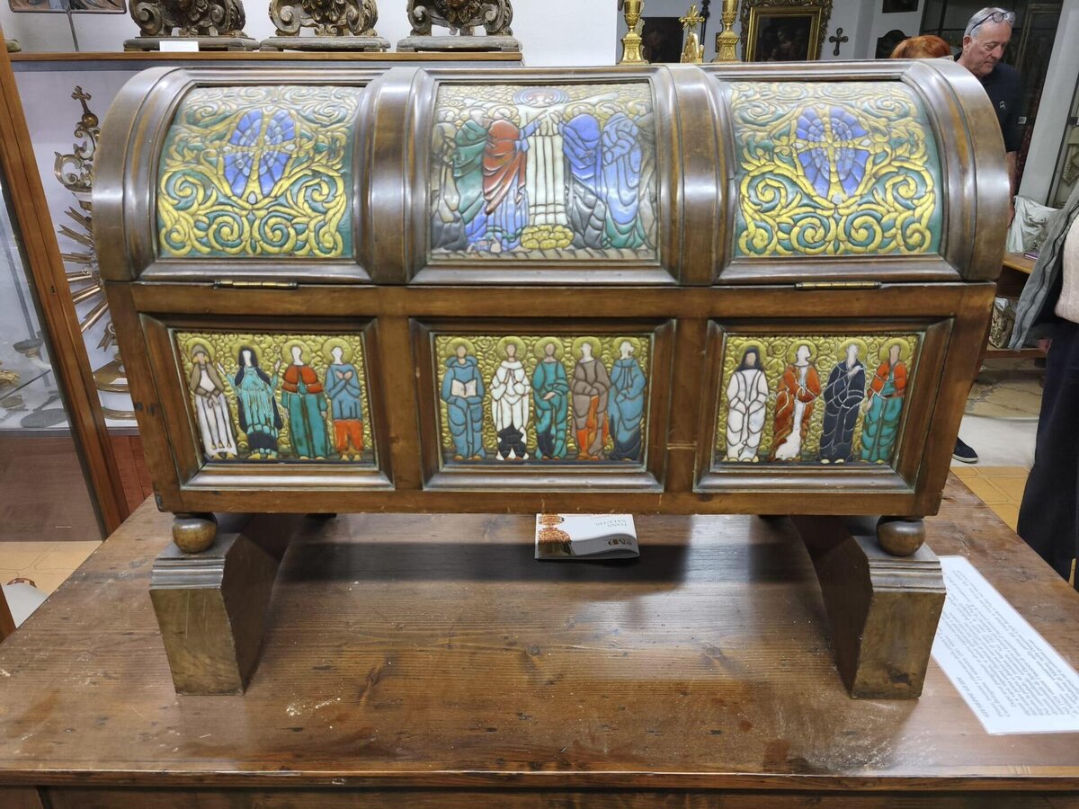 Cassapanca in legno con pannelli decorati da figure e motivi colorati.
