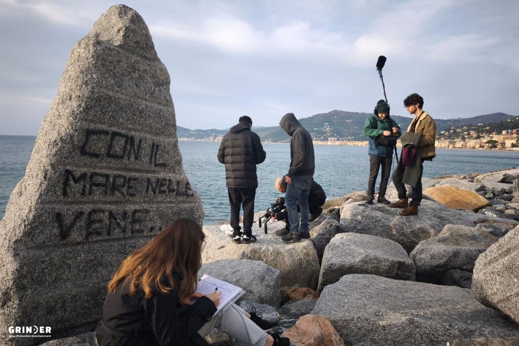 Personnes sur des rochers au bord de la mer avec écriture italienne.