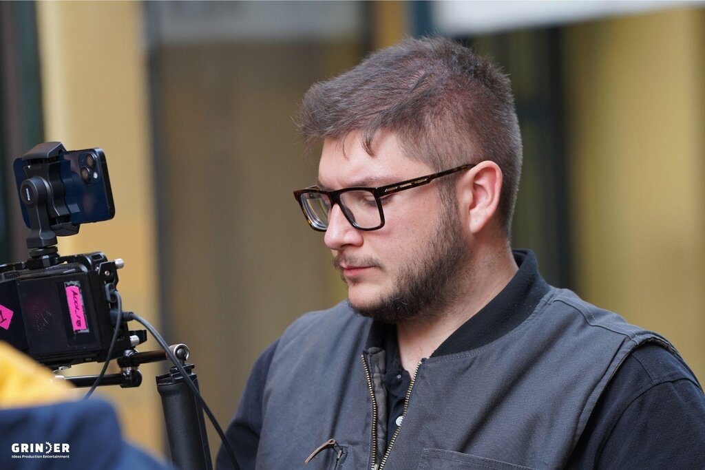 Jeune homme avec lunettes utilisant une caméra montée sur un trépied.